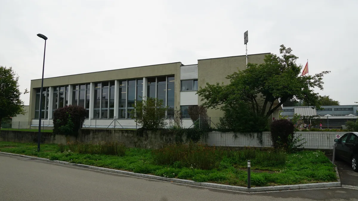 Eine Turnhalle von aussen: ein Betonbau aus dem Jahr 1961 mit grossen Fenstern.